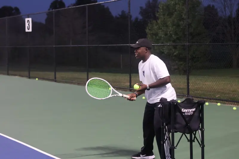 Coach feeding balls during an evening session