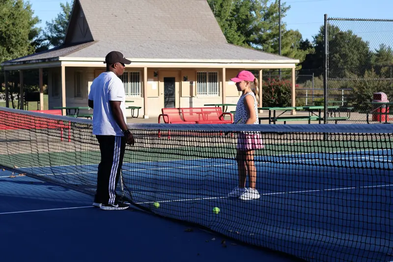 Coach Kuda Sandi talking with a junior player across the net