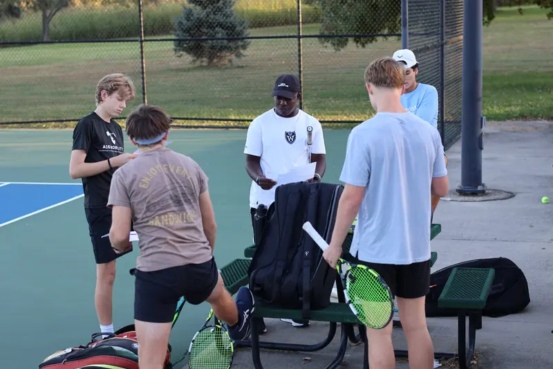 Coach reviewing written session plans with a group of players