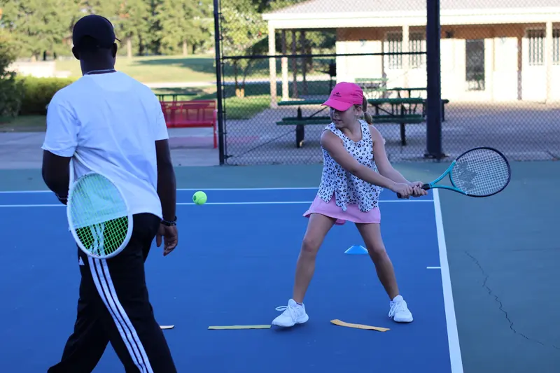 Junior player hitting a two-handed backhand during a coached drill